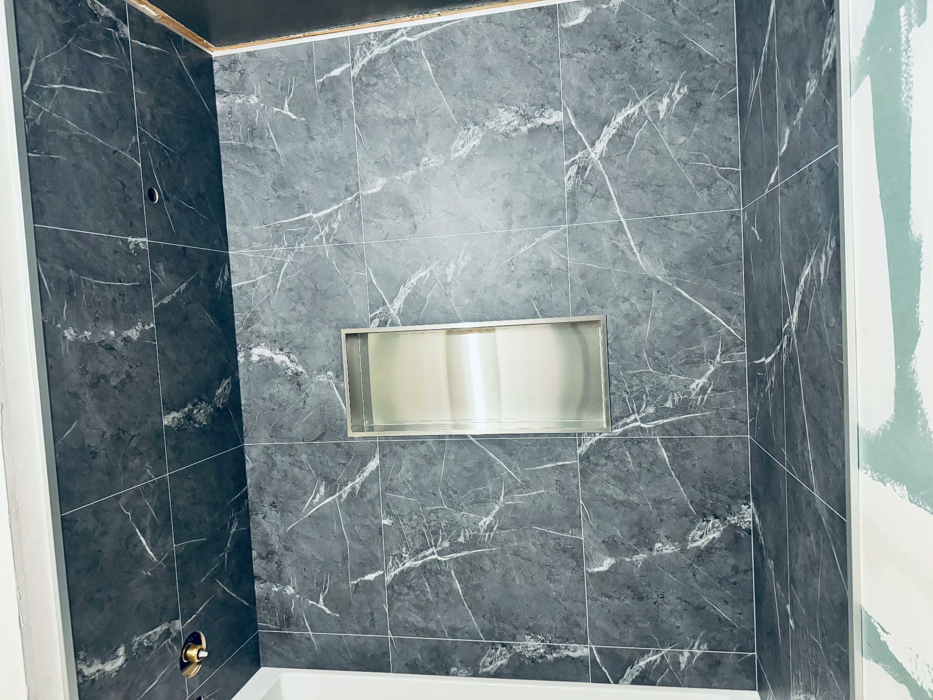 Charcoal marble-look tile shower with stainless niche