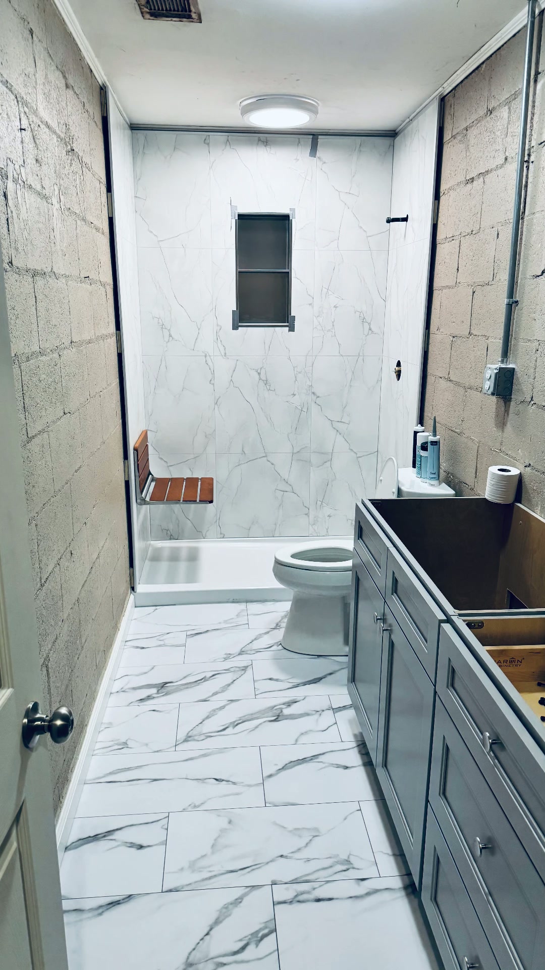 Bathroom renovation with marble-look shower surround and flooring