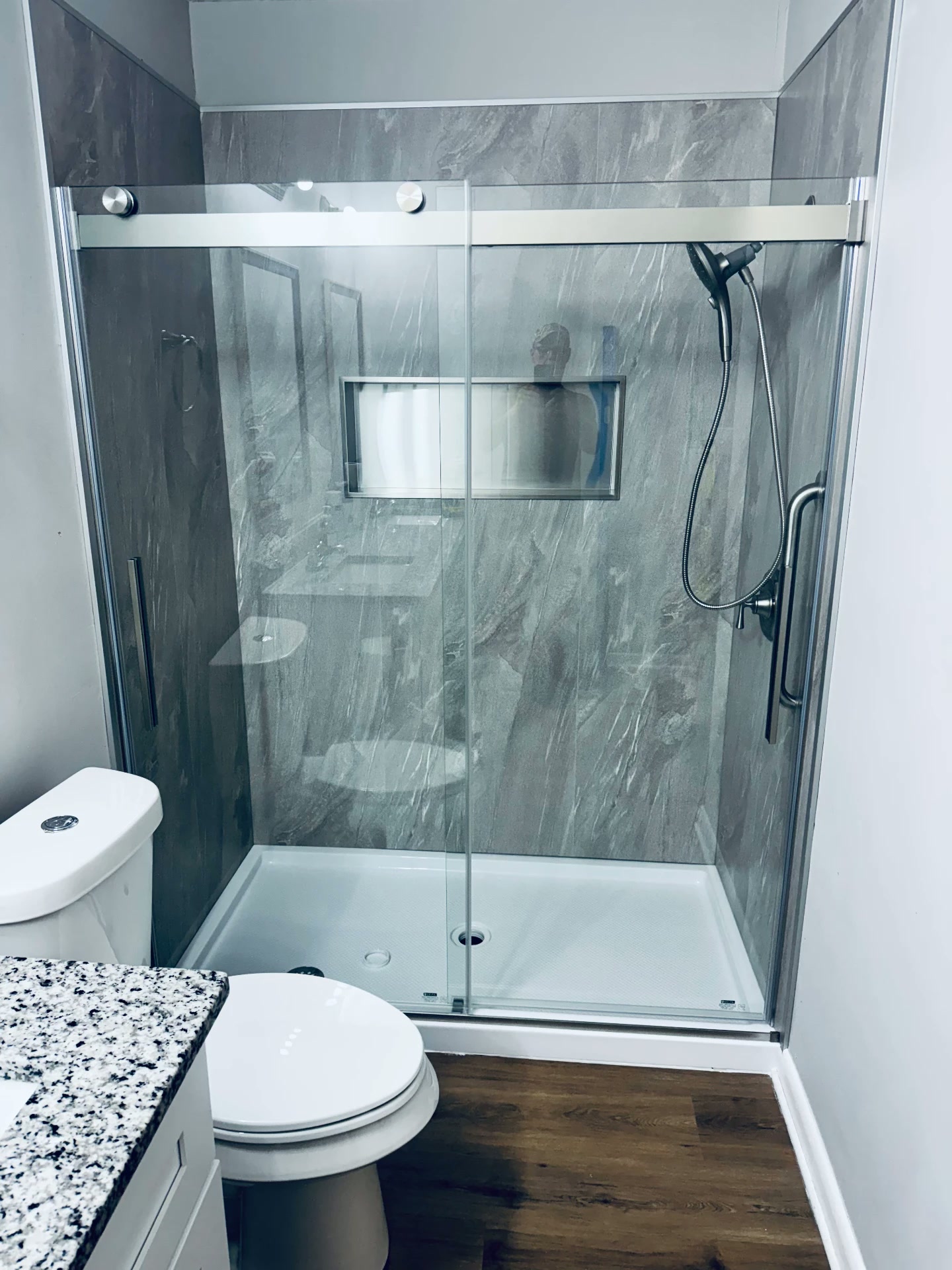 Completed gray tile shower with sliding glass enclosure